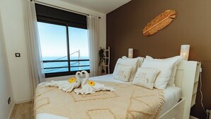 Een slaapkamer met een bed, uitzicht op zee en een bruine muur.