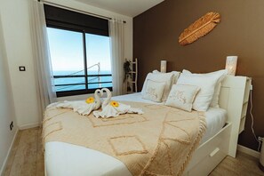 A bedroom with a bed, a view of the sea, and a brown wall. - Villa Bleue Camaïeu - Sea view, heated pool and pétanque court... (Saint-Leu)