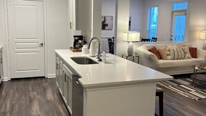 Eine moderne Küche mit Kochinsel, ein Essbereich mit einer Couch und ein Wohnzimmer mit Couchtisch.