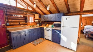 A cabin-style kitchen with wooden cabinets, a stove, a refrigerator, and a sink. - Cozy Adirondack Cabin-Lakeside Resort Camp 3 (Olmstedville)