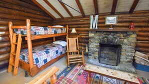 A log cabin interior with bunk beds, a stone fireplace, a wooden ladder, and a framed picture on the wall. - Cozy Adirondack Cabin-Lakeside Resort Camp 3 (Olmstedville)