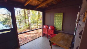 A cabin with a wooden interior, a table, and red chairs. - Cozy Adirondack Cabin-Lakeside Resort Camp 3 (Olmstedville)