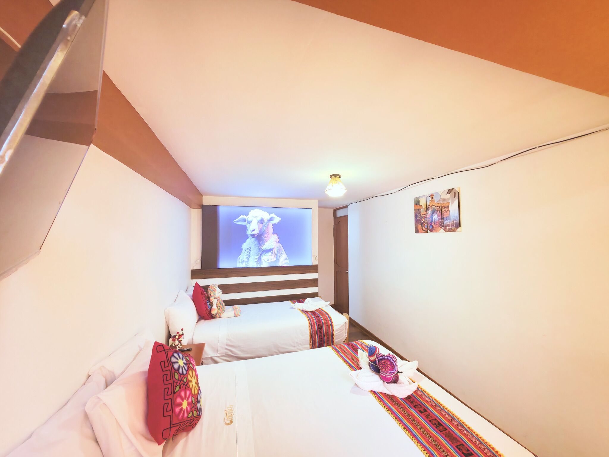 A hotel room with two beds, a TV on the wall, and a small wall art piece.