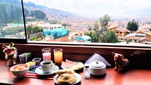 A breakfast table with food and drinks, a window with a city view. - Mirador All Sur Cusco (Cusco)