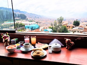 A breakfast table with food and drinks, a window with a city view. - Mirador All Sur Cusco (Cusco)