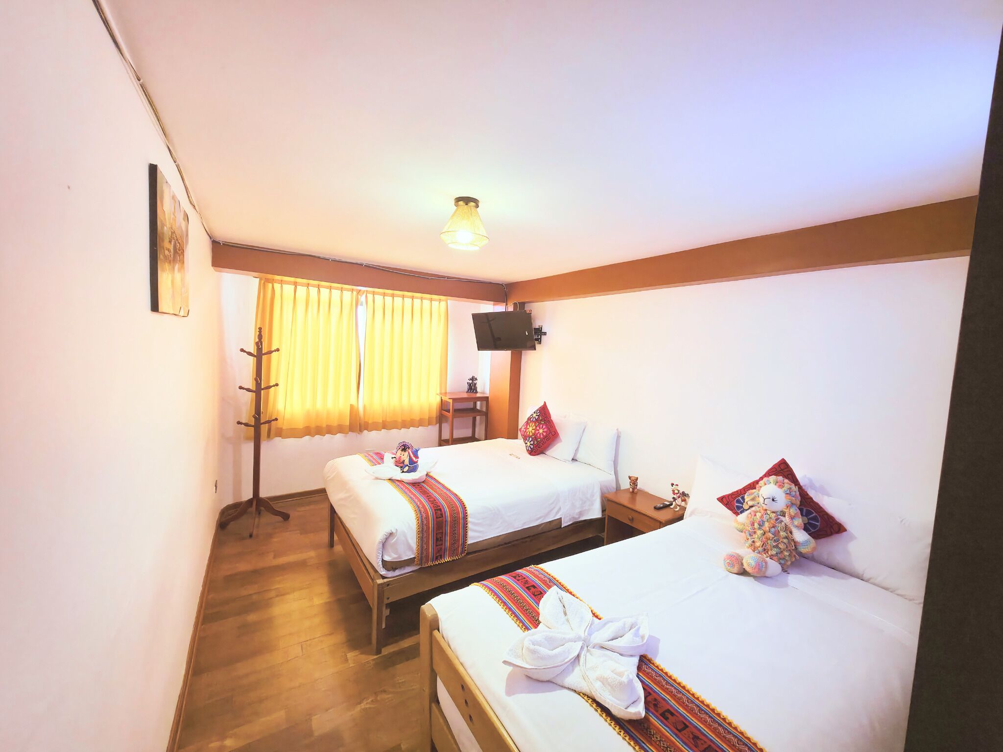 Habitación de hotel con dos camas, un escritorio, una silla, un televisor y una ventana con cortinas.