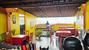 A restaurant with a high ceiling, yellow walls, and a view of the sea. - Mirador All Sur Cusco (Cusco)