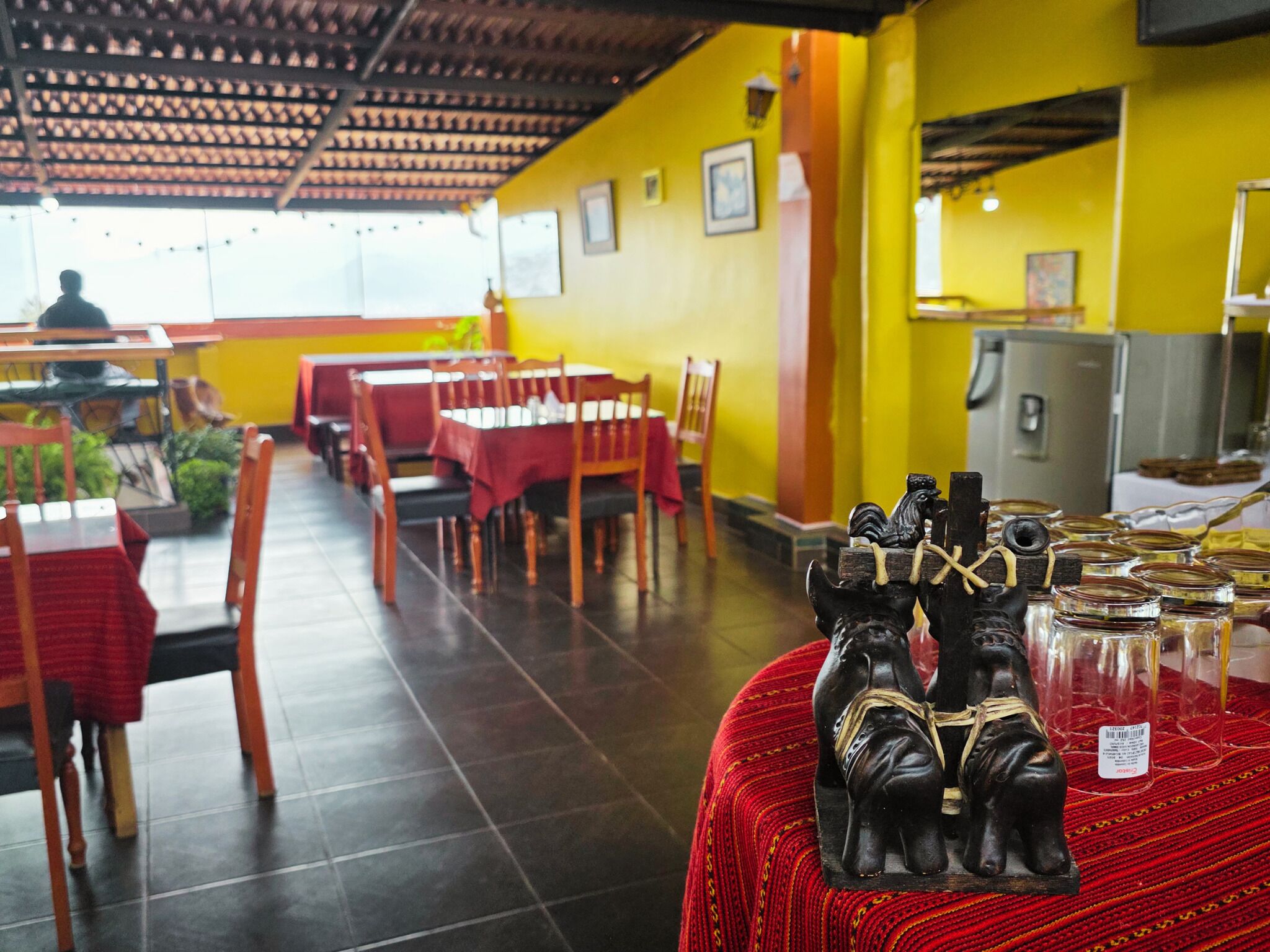 Un restaurante con mesas y sillas, piso de baldosas y un techo con diseño decorativo.