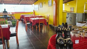 Un restaurante con mesas y sillas, piso de baldosas y un techo con diseño decorativo.