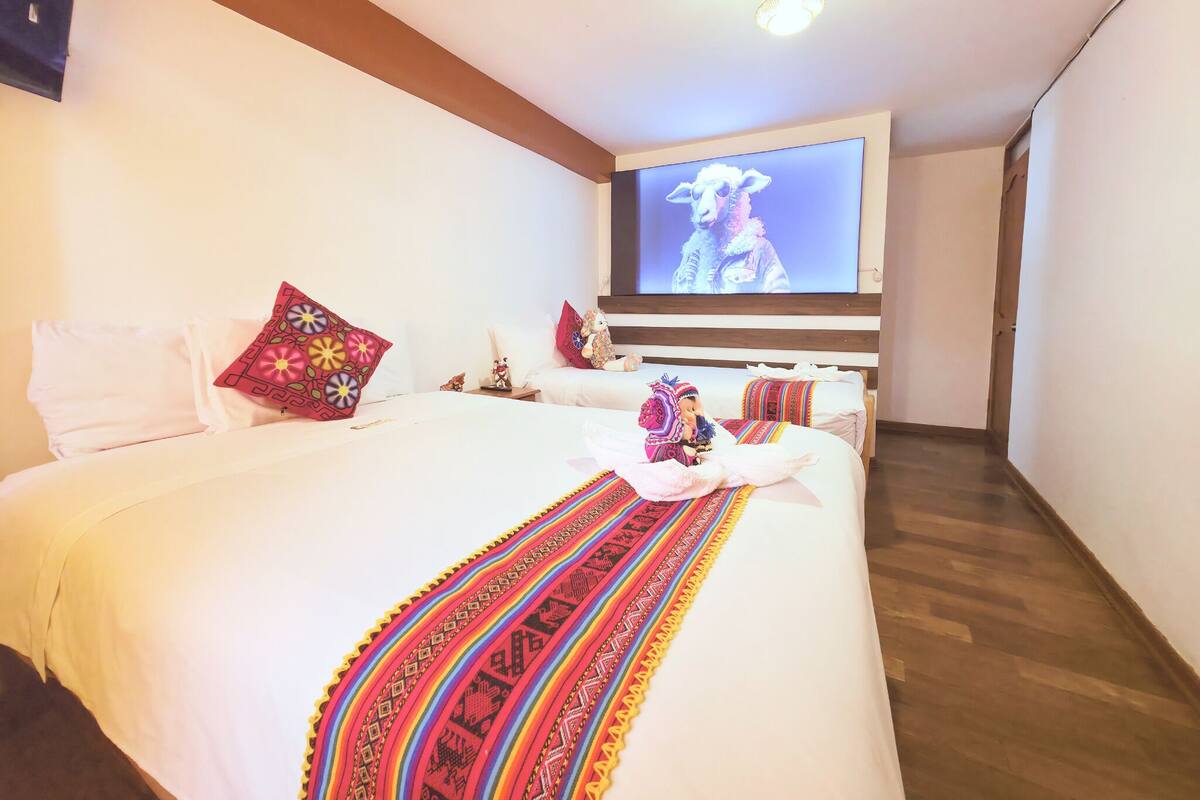 A hotel room with a large bed, a television mounted on the wall, and a wooden ceiling.
