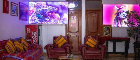 A living room with a sofa, two armchairs, a coffee table, and a television displaying a colorful image.