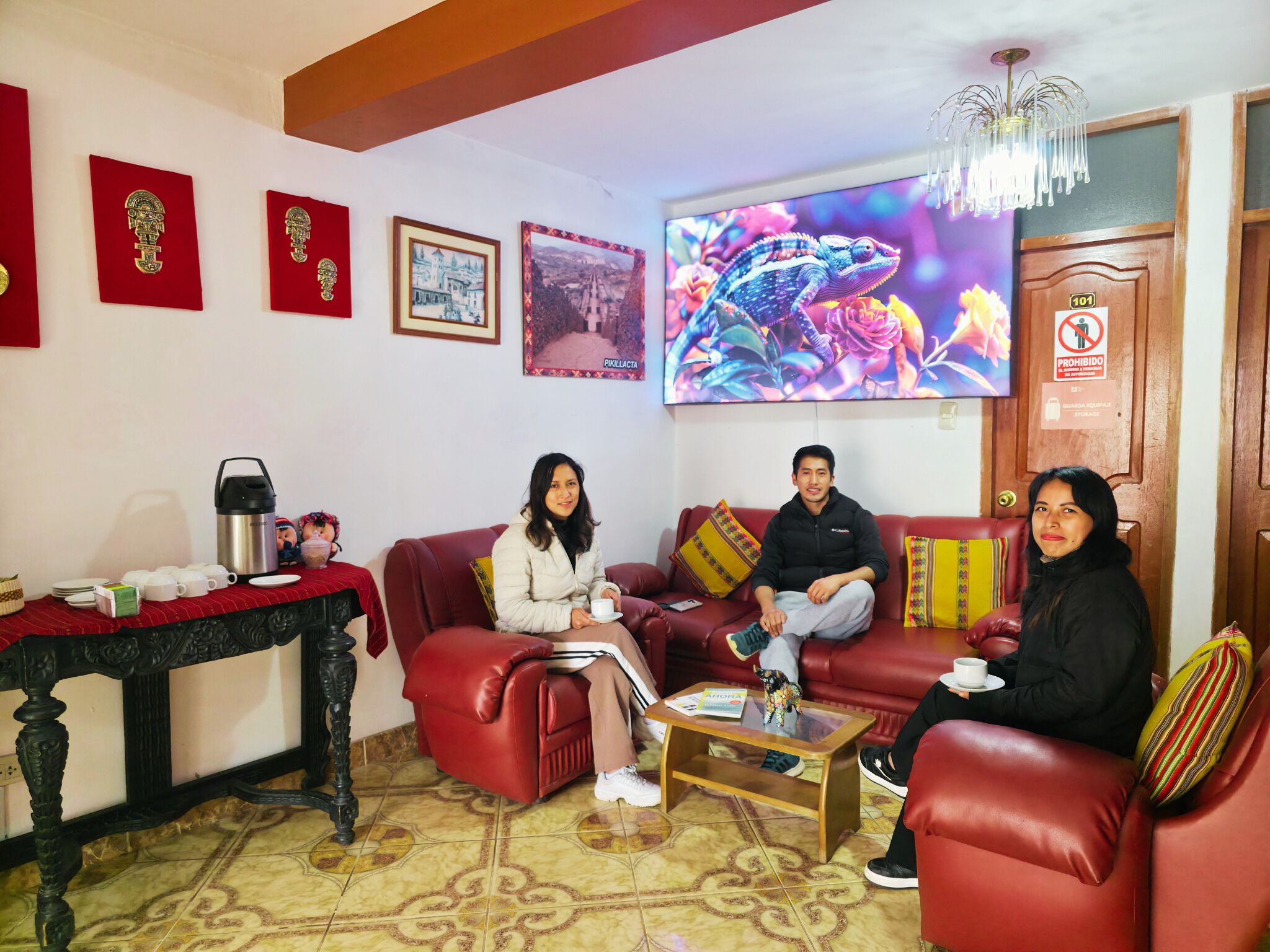 A living room with a red sofa, a coffee table, and a TV displaying a chameleon.