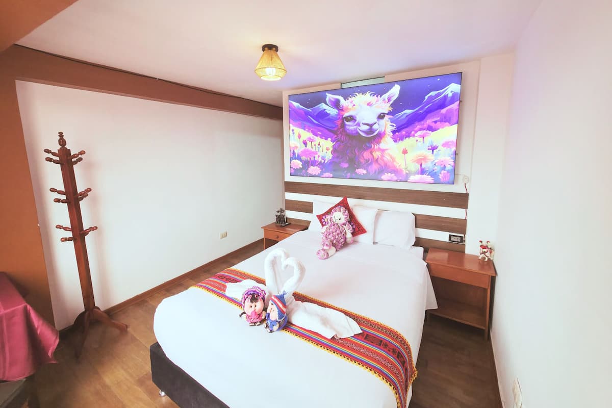 A hotel room with a bed, a television, a coat rack, and a small table.
