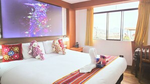 A hotel room with a large bed, a flat-screen TV, a view of the city, and a wooden floor. - Mirador All Sur Cusco (Cusco)