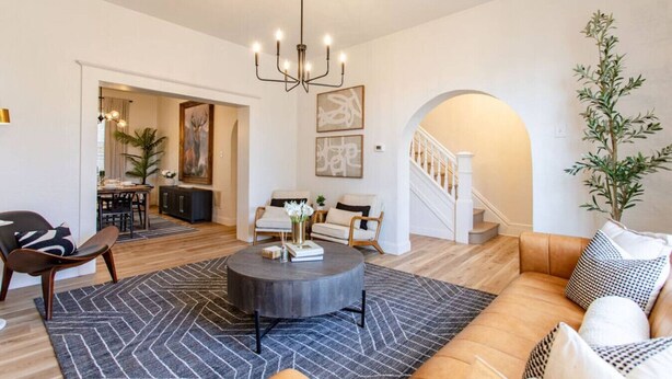 Een moderne woonkamer met een ronde salontafel, een bank en een trap naar een ander niveau.