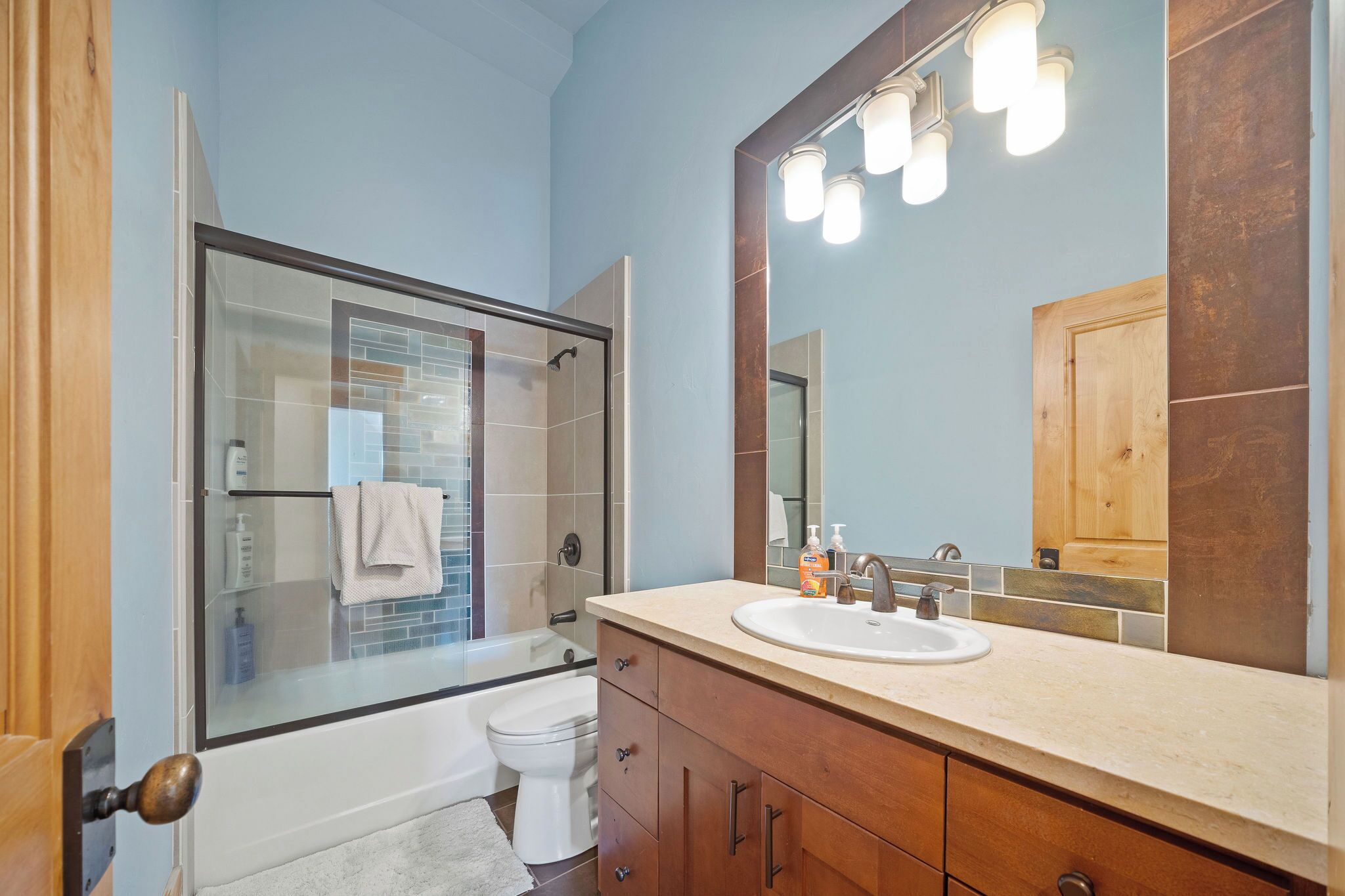 Une salle de bain avec une douche à parois de verre, des toilettes blanches, un meuble-lavabo et un grand miroir.