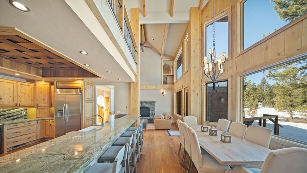 Une cuisine spacieuse avec un grand îlot central, des meubles en bois et une grande fenêtre donnant sur un paysage enneigé.