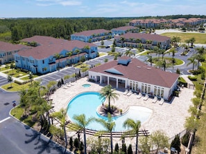 A residential complex with multiple two-story buildings, a central swimming pool, and a parking area. - Comfortable 3BR Townhome Near Parks, Great Value (Kissimmee)
