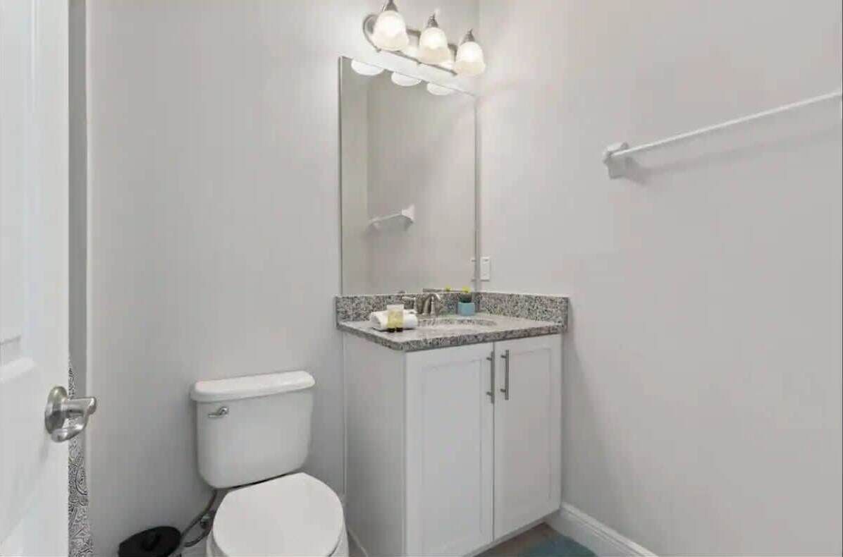 Une salle de bain comprenant des toilettes, un lavabo avec un miroir et un porte-serviettes.