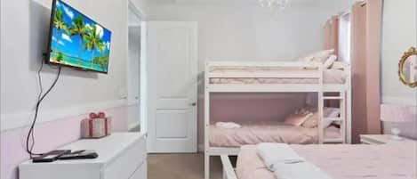 Un dormitorio con literas, televisor, cómoda y candelabro.