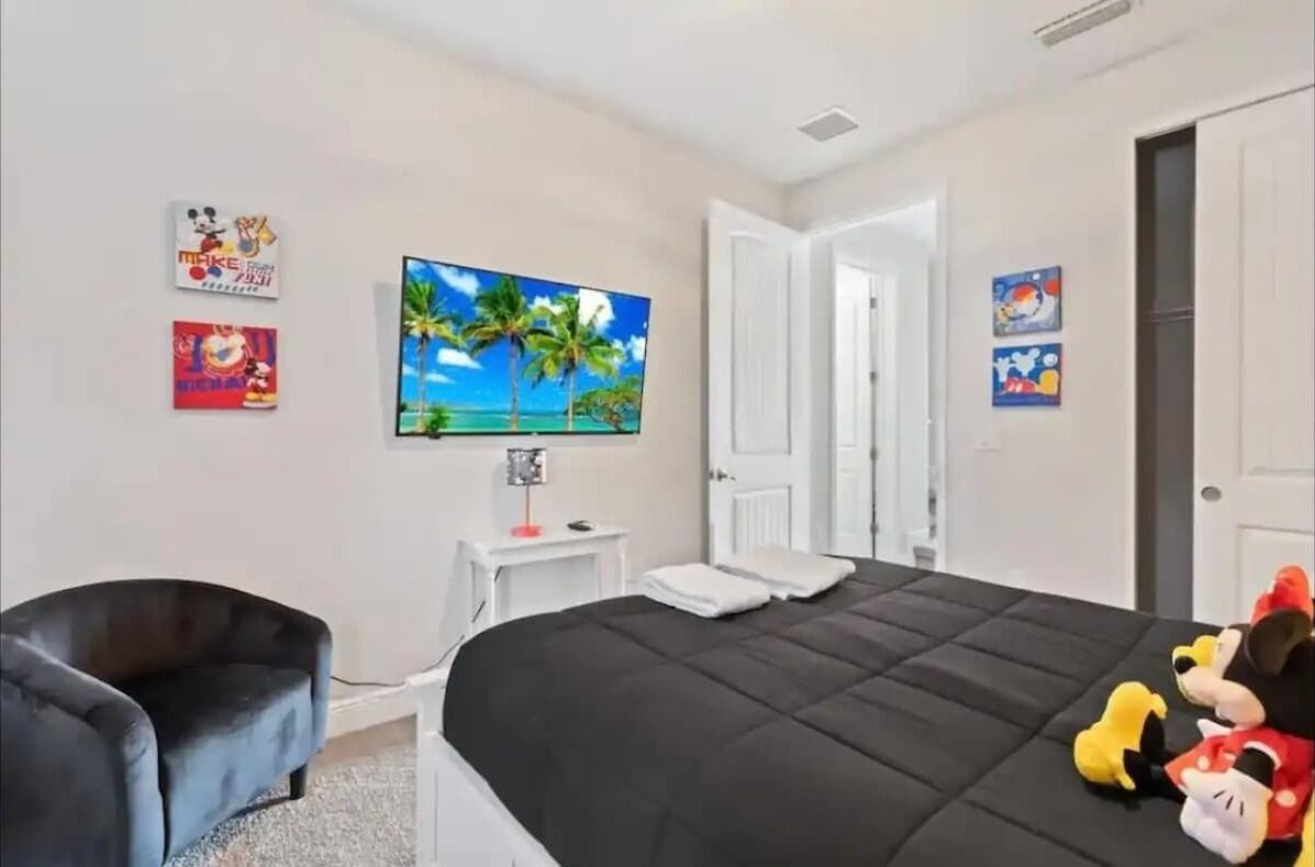 Een slaapkamer met een bed, een televisie, een bureau en een stoel.