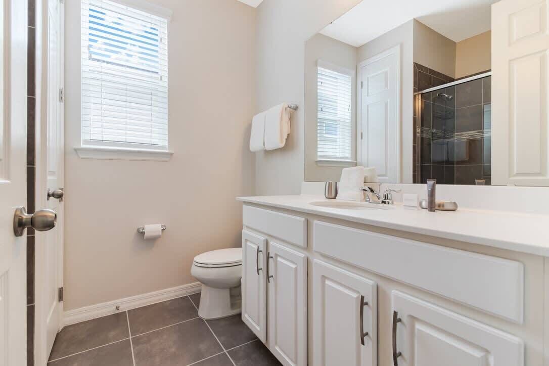 A bathroom with a toilet, a sink with a mirror, and a shower area.