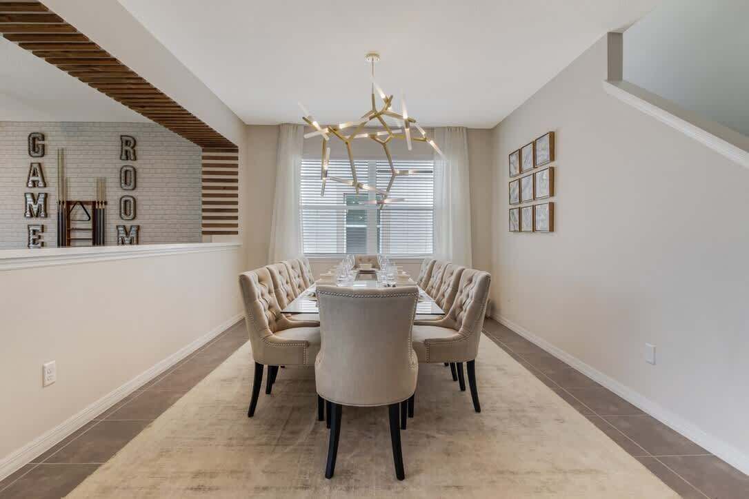 Une salle à manger avec une longue table, six chaises et un lustre.