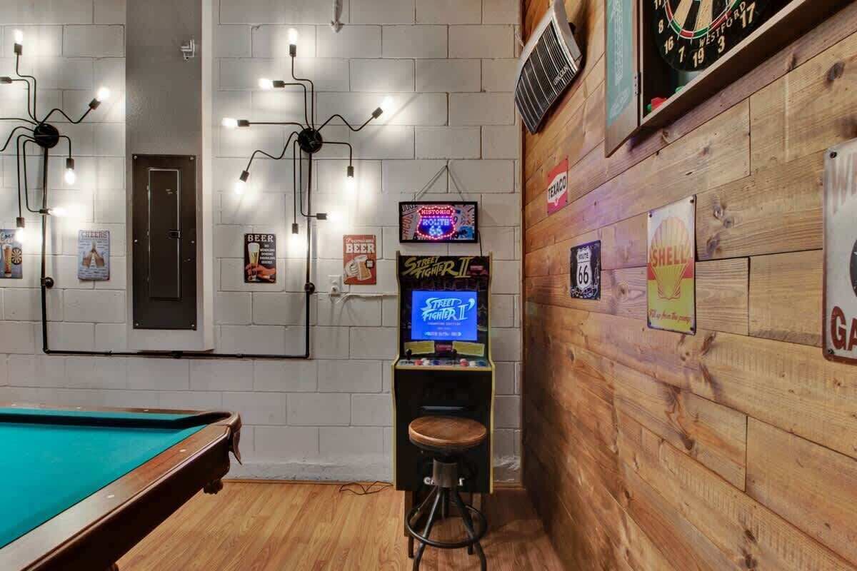 Ett biljardbord, en bardisk med barstolar och en neonreklamskylt för arkadspelet ”Street Fighter II”.