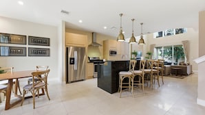 A modern kitchen with a central island, stainless steel appliances, and pendant lighting. - Magic Village 4br, Spacious and Stylish (Kissimmee)