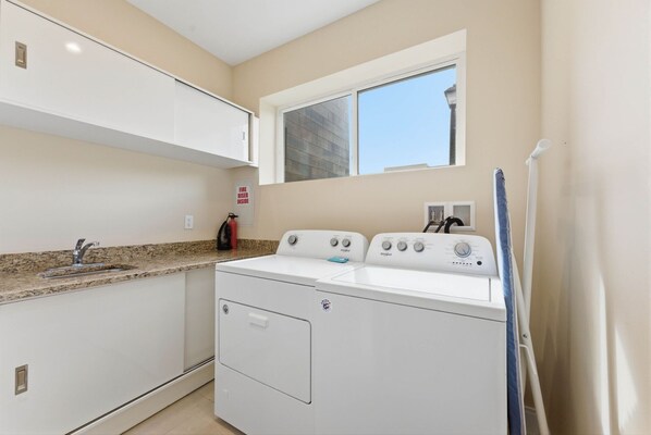 A laundry room with a washer and dryer, a window, and a sink. - Magic Village 4br, Spacious and Stylish (Kissimmee)