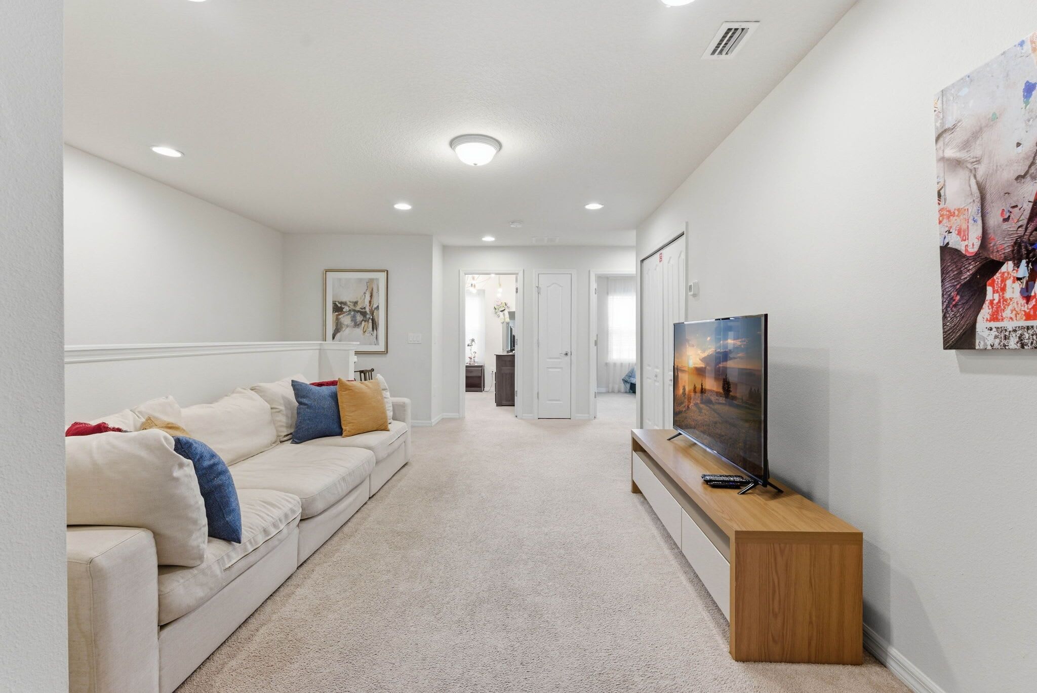 A modern living room with a sofa, TV, and artwork.
