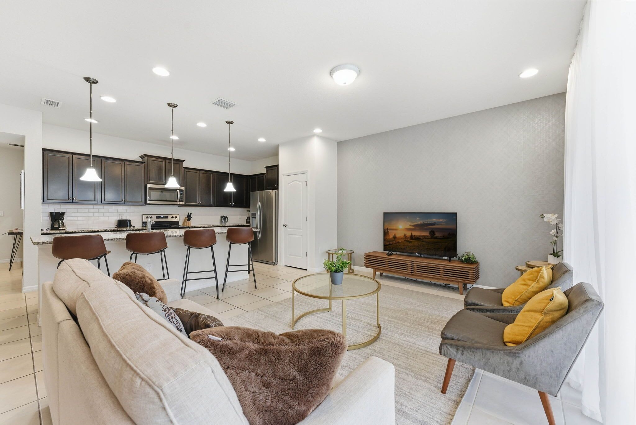 A modern living room with a sofa, armchairs, a coffee table, and a TV.