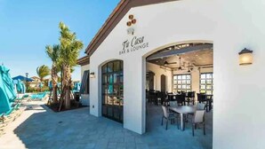 A bar and lounge area with outdoor seating, a poolside view, and a clear sky. - Cozy and Spacious 5BR With Pool Near Disney Parks (Kissimmee)