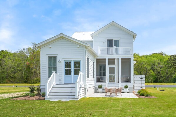 A two-story house with a front porch, a balcony, and a small garden area.