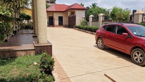 Uma entrada de garagem residencial com um carro vermelho estacionado à direita.