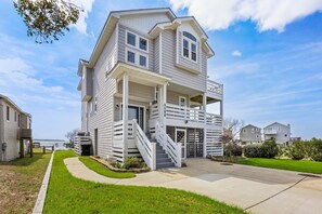 A two-story residential building with a front porch, a staircase, and a visible number '218'. - Bay Dreams Soundfront Escape w/ Beach Parking & Sunsets (Kill Devil Hills)
