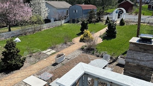 A residential property with a paved patio, outdoor seating, a fenced yard, and a small shed.