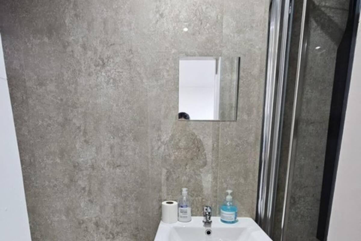 A bathroom with a white sink, toilet, and a glass shower enclosure.
