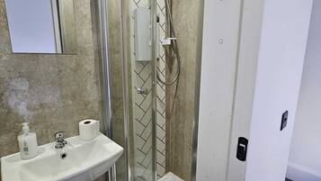 A bathroom with a glass-enclosed shower, a sink with a mirror, and a towel rack.