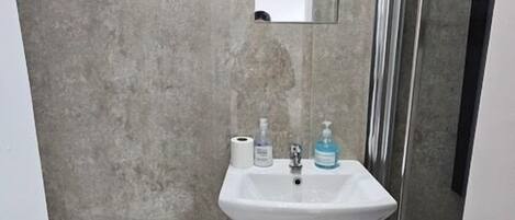 Un baño con lavamanos pedestal, inodoro y cabina de ducha de cristal.
