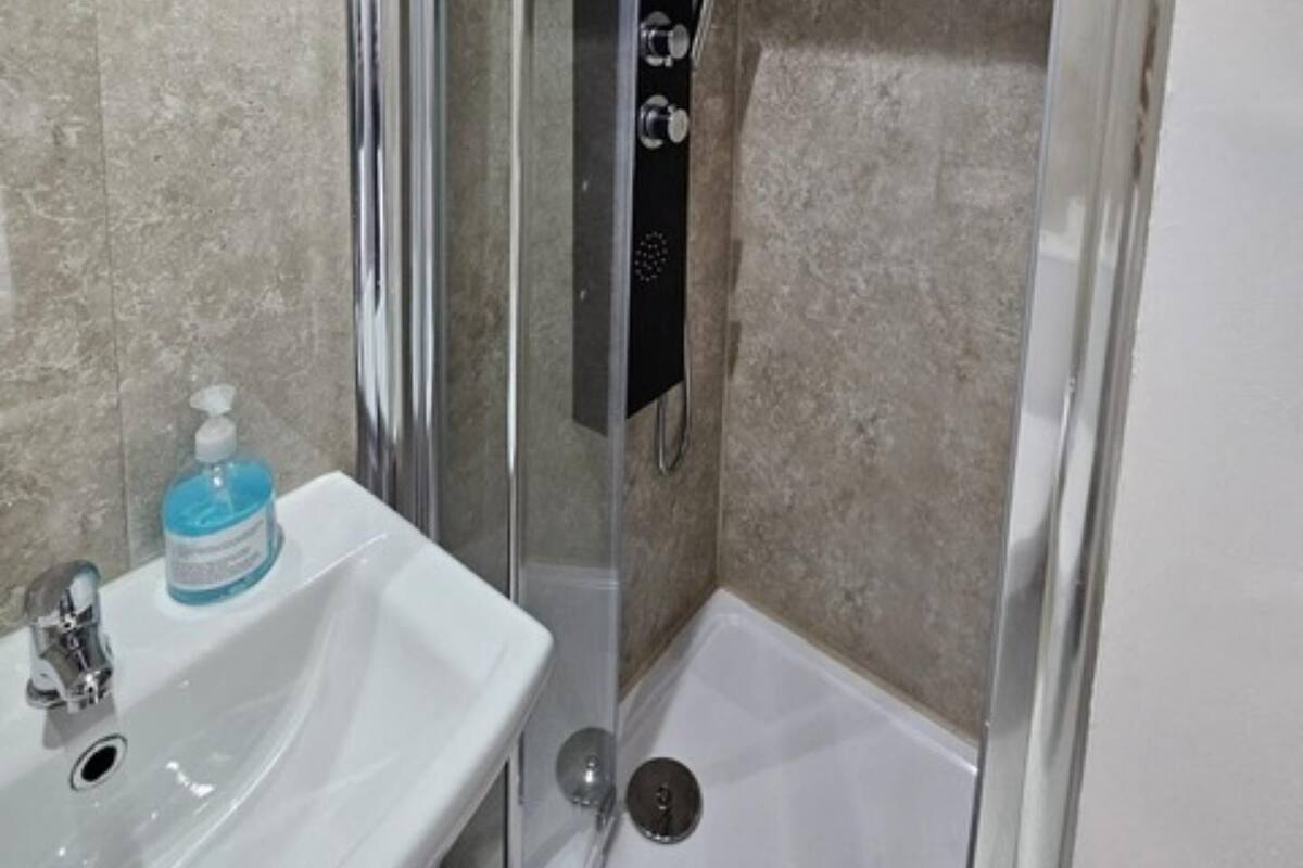 A bathroom with a glass-enclosed shower, a white sink, and a mirror.