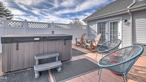 Ett bubbelbad med trappsteg, två Adirondack-stolar och en uteplats med ett trädäck och ett metallgaller.