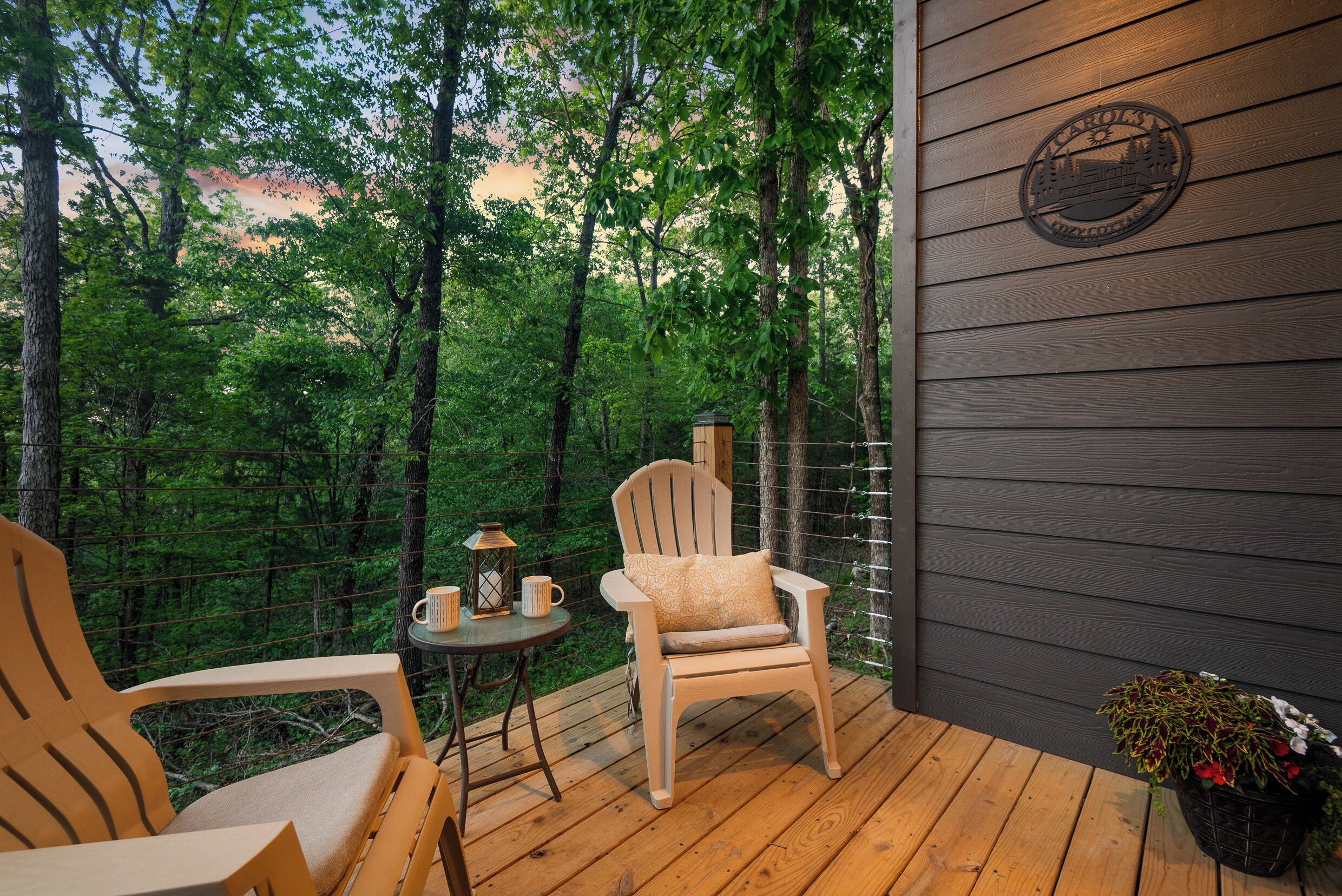 A wooden deck with a chair and table, surrounded by a forest.