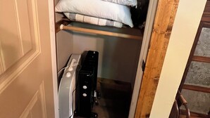 A small, narrow closet with a wooden ladder, a shelf with white pillows, and a black appliance on the floor. - Cozy Ozark Cottage Near Spring River & Mammoth Spring (Mammoth Spring)