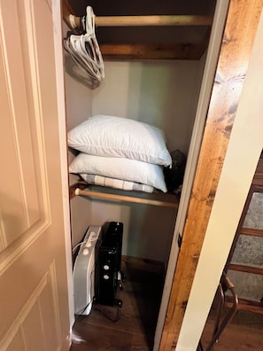 A small, narrow closet with a wooden ladder, a shelf with white pillows, and a black appliance on the floor. - Cozy Ozark Cottage Near Spring River & Mammoth Spring (Mammoth Spring)