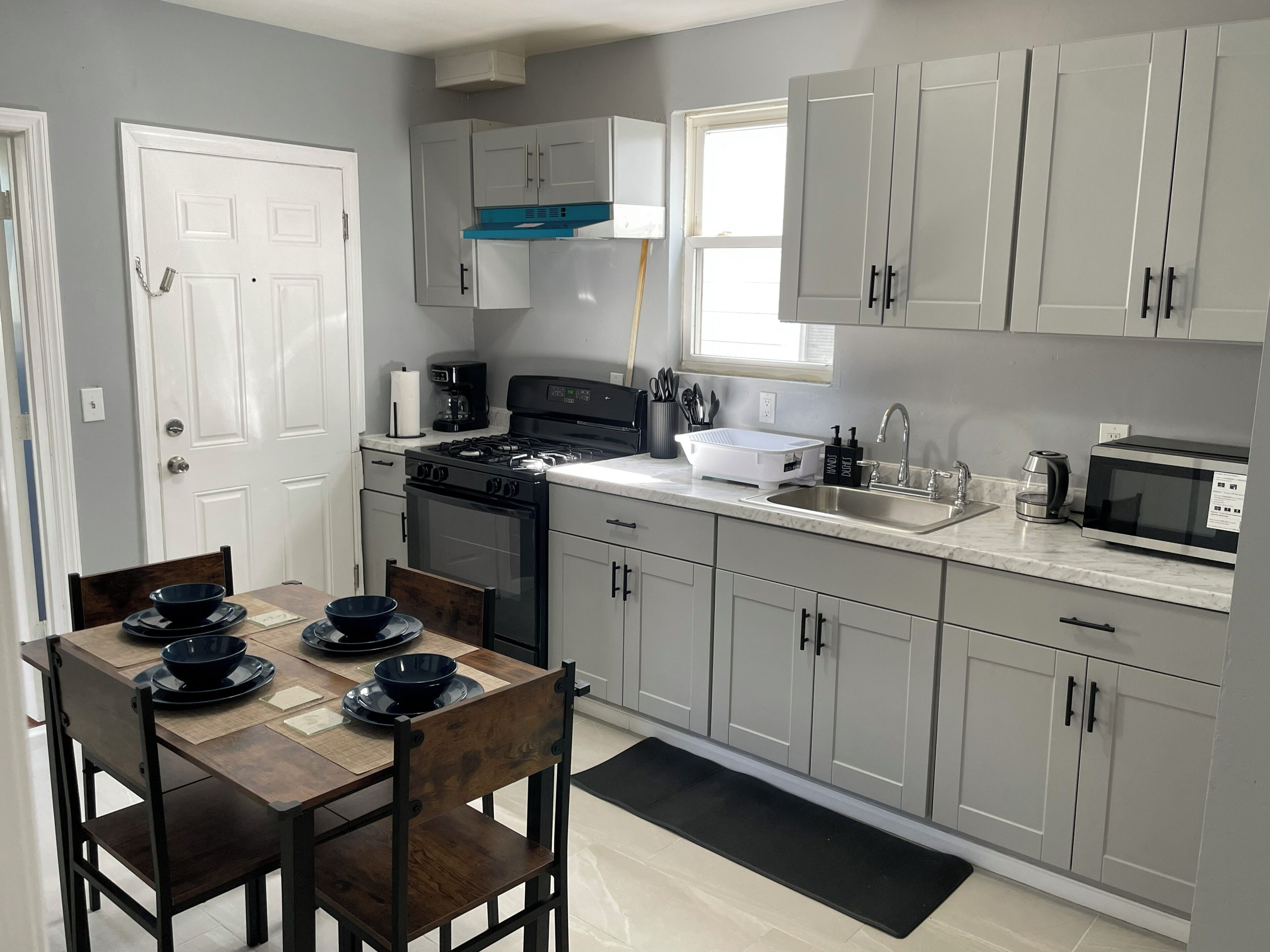 A compact kitchen with a dining table, chairs, a stove, a sink, and cabinets.