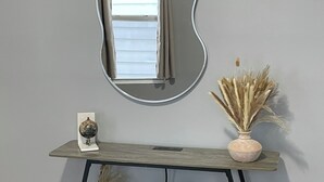Een houten consoleschrank met een spiegel, een wereldbol en een vaas met gedroogde planten.