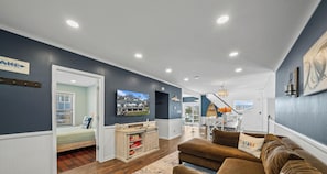 A living room with a brown couch, a wooden cabinet, and a television mounted on the wall. - Spacious Home w/Hot Tub, Quick Walk to Fontana Nightlife, Marina, Dining, & Abbey Resort (Fontana-on-Geneva Lake)