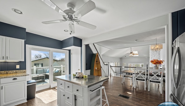 A spacious kitchen with a central island, a dining area with a chandelier, and a view of the outdoors. - Spacious Home w/Hot Tub, Quick Walk to Fontana Nightlife, Marina, Dining, & Abbey Resort (Fontana-on-Geneva Lake)