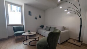 En moderne stue med en sofa, to lænestole, et lille bord og en gulvlampe.